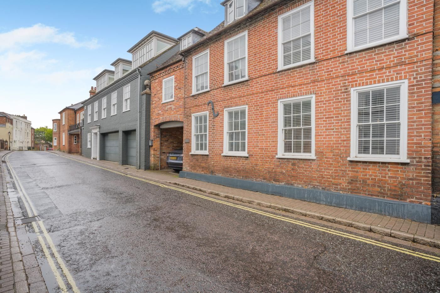 A street with a row of brick buildings, one with a garage door and another with a visible number.
