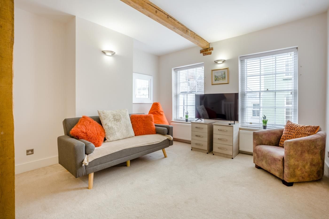 A living room with a sofa, armchair, and a TV on a stand.