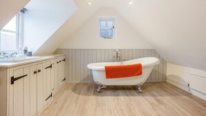 Un bagno con una vasca freestanding, una finestra e un mobile lavabo bianco con pensili.
