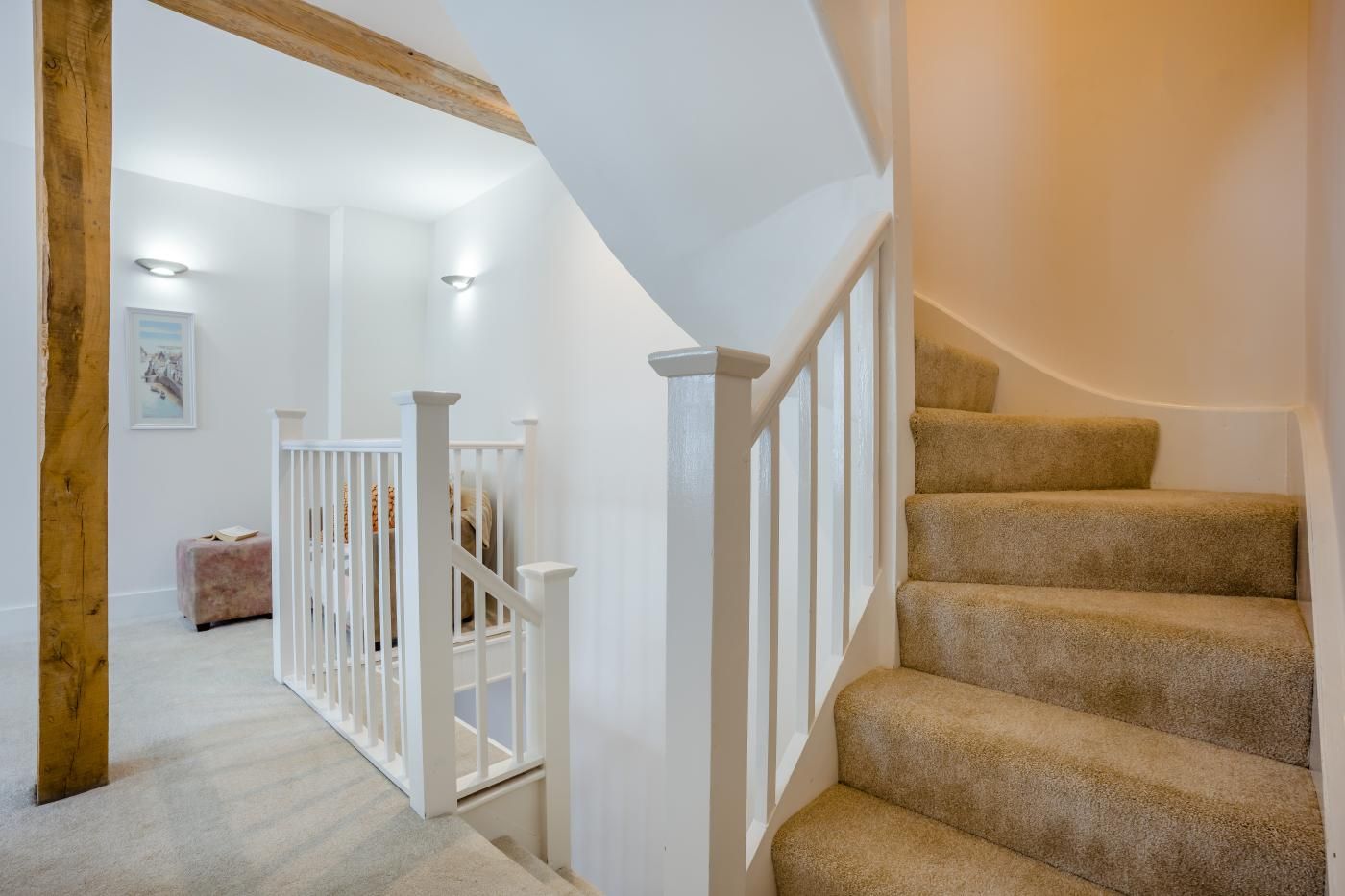 A staircase with white railings and beige carpeted steps leading to a landing.