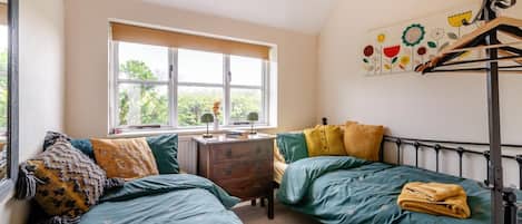 A room with two beds, a window, a dresser, and a wall-mounted rack.