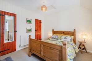 Ein Schlafzimmer mit einem hölzernen Bett, zwei Nachttischlampen, einem Spiegel und einer Tür mit rotem Rahmen.