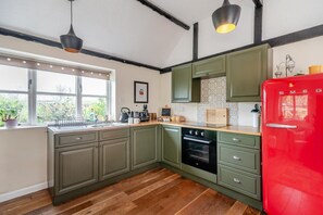 Eine Küche mit grünen Schränken, einem roten Kühlschrank und einem Fenster mit Pflanzen.