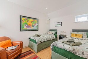 Ein Schlafzimmer mit zwei Betten, einem Sessel, einem Teppich und einem Bild an der Wand.