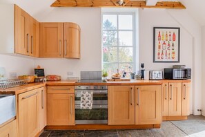 Eine Küche mit Holzausstattung, einem Backofen, einer Mikrowelle und einem Fenster.