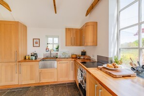 Eine moderne Küche mit Holzschränken, einer Spüle aus Edelstahl und einem großen Fenster.