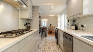Una cocina moderna con estufa a gas, lavavajillas y un comedor con mesa y sillas.