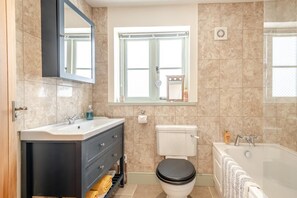 Un bany amb un lavabo, vàter, banyera i una finestra amb vistes.