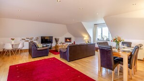 A modern living room with a fireplace, a dining area, and a TV. - 2 Bed in Fowey (oc-p00761) (Fowey)