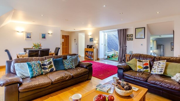 A spacious living room with leather sofas, a coffee table, and a bookshelf. - 2 Bed in Fowey (oc-p00761) (Fowey)