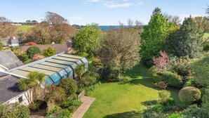 A residential property with a large glass conservatory, a well-maintained garden, and a view of the sea. - 2 Bed in Fowey (oc-p00761) (Fowey)