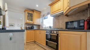 A kitchen with wooden cabinets, a gas stove, an oven, and a microwave. - 1 Bed in Ambleside (oc-lr077) (Ambleside)