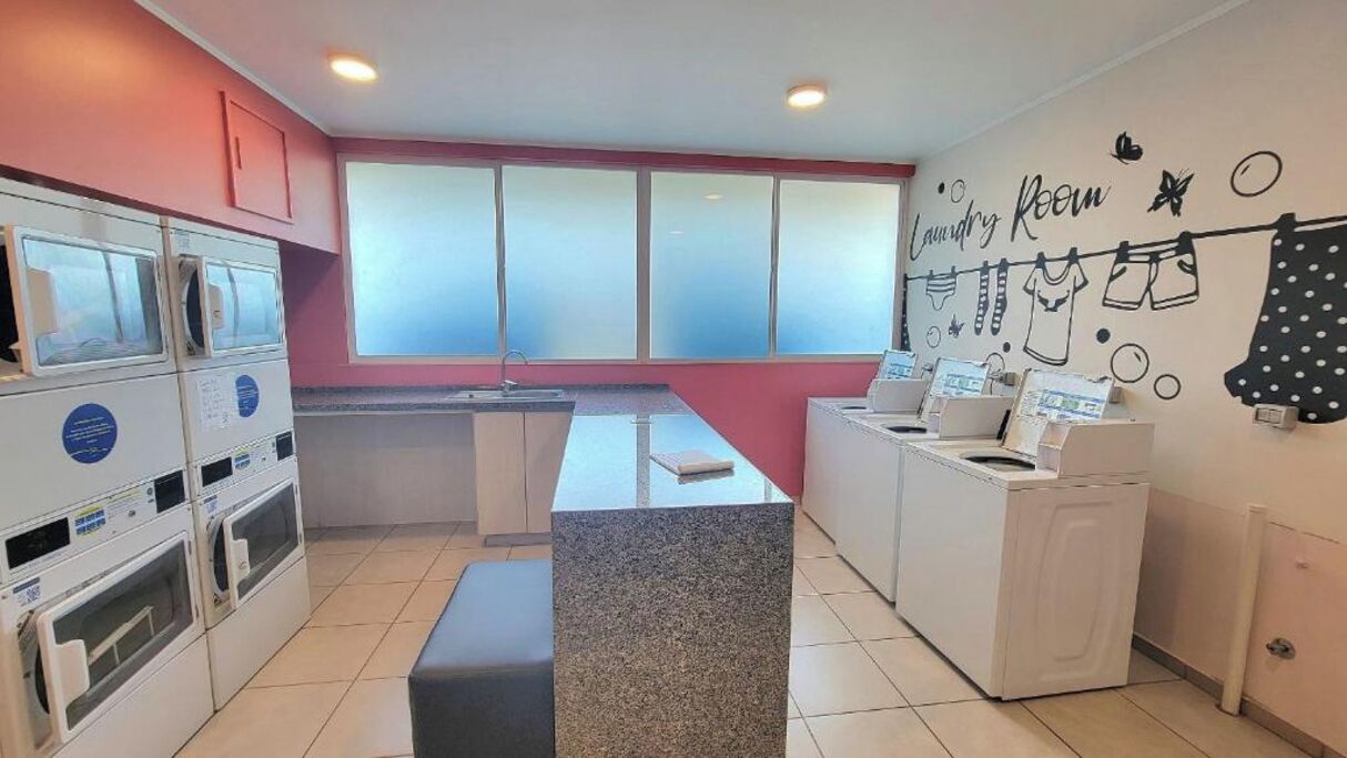 A laundry room with a countertop, washing machines, and a wall with laundry-themed decorations.