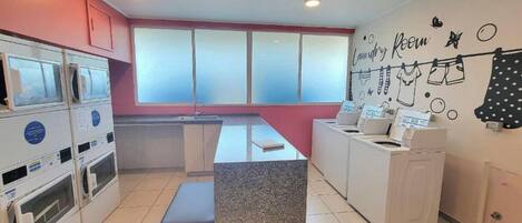 Un lavadero con mostrador, lavadoras y una pared decorada con motivos de lavandería.
