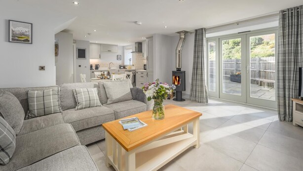 A modern living room with a sofa, a wooden coffee table, and a fireplace. - 2 Bed in Easington (oc-coq114) (Easington)