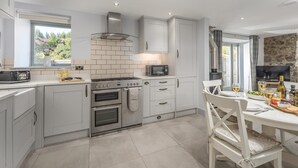 A modern kitchen with white cabinetry, a built-in oven, a microwave, and a dining area with a table set for two. - 2 Bed in Easington (oc-coq114) (Easington)