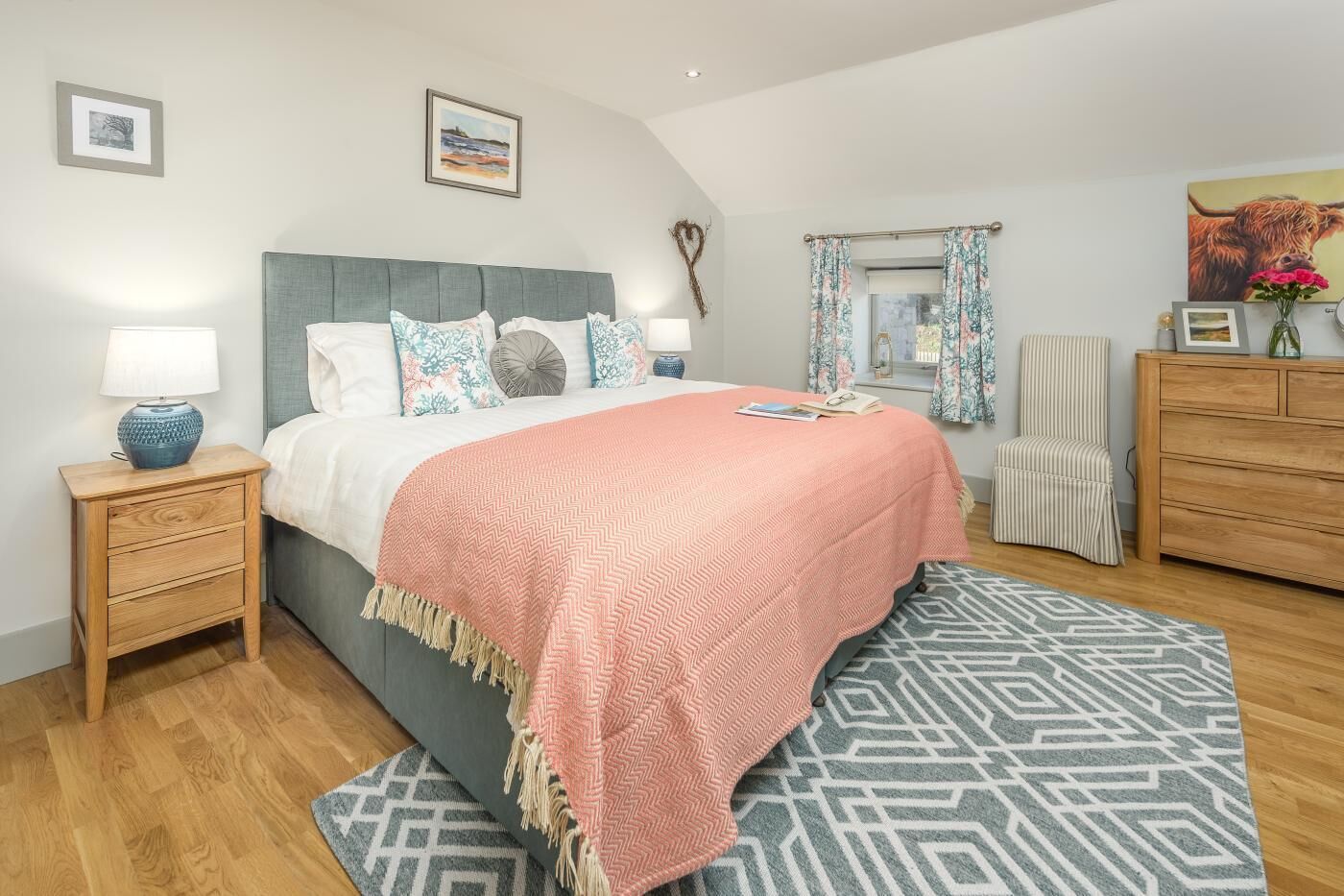 A bedroom with a bed, bedside tables, a dresser, a chair, and a window with curtains.
