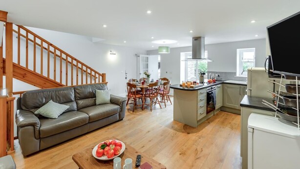 Um apartamento moderno com sala de estar, sala de jantar, cozinha e uma escada.