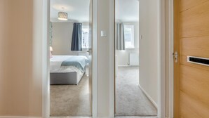 Een slaapkamer met een bed, een radiator en een raam met gordijnen.