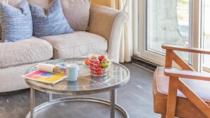 A living room with a sofa, a glass coffee table, a chair, and a window with curtains. - 1 Bed in Lamorna Cove, (oc-h40239) (Lamorna)