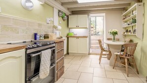 A kitchen with a stove, oven, and a dining table with chairs. - 2 Bed in Buxton (oc-dcbap) (Crowdecote)