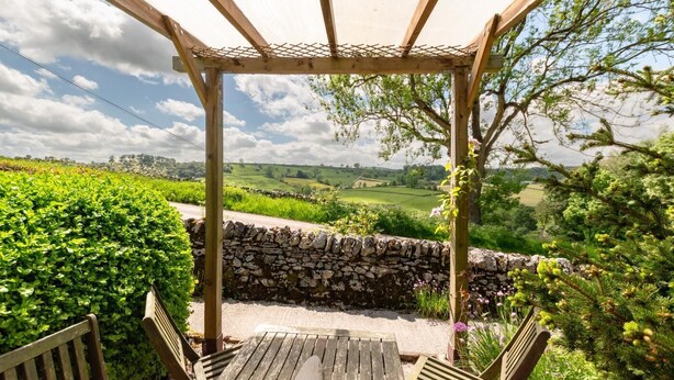 A wooden pergola with a view of a rural landscape, stone wall, and a bench. - 2 Bed in Buxton (oc-dcbap) (Crowdecote)