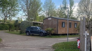 Un paysage rural avec un bâtiment en bois, une voiture garée et un chemin de gravier.