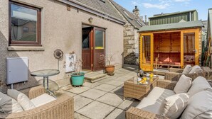 A cozy outdoor seating area with wicker furniture, a table, and potted plants. - 3 Bed in Pitlochry (oc-t37864) (Pitlochry)