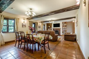A dining area with a table set for four, a fireplace, a television, and a bookshelf. - 3 Bed in Acle (oc-b41410) (Acle)