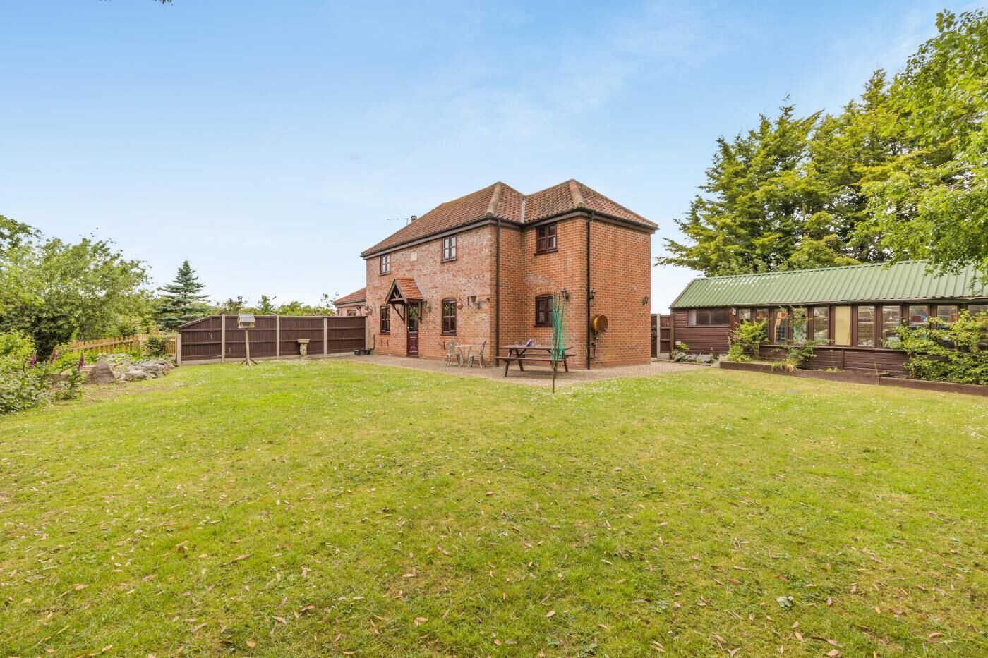 A brick building with a small attached structure, surrounded by a grassy yard.
