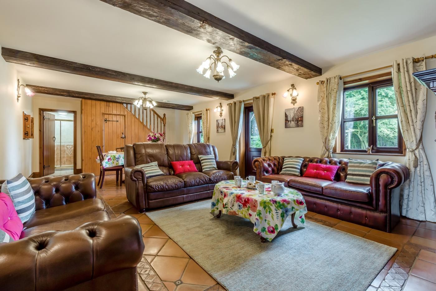 A spacious living room with leather sofas, a coffee table, and a staircase leading to another level.