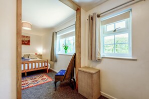 Ein Kinderzimmer mit Etagenbett, Schreibtisch, Stuhl, kleinem Teppich und einem Fenster mit Vorhängen.