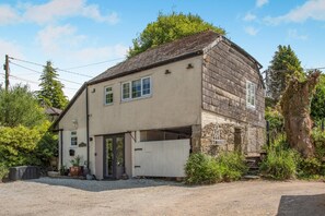 A two-story house with a garage, surrounded by greenery and a gravel driveway. - 1 Bed in Upton Cross (oc-c34217) (Caradon Town)