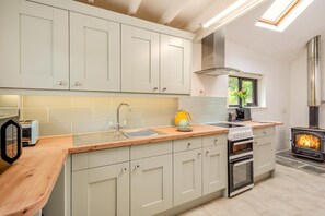 A modern kitchen with light-colored cabinets, a wooden countertop, a built-in stove, and a skylight. - 1 Bed in Upton Cross (oc-c34217) (Caradon Town)