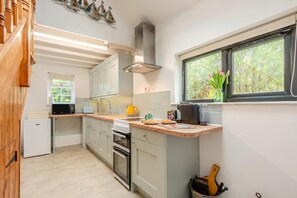 A compact kitchen with a microwave, toaster, stove, and a small refrigerator.