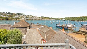 Ein Hafen mit Booten, ein Gebäude mit schrägem Dach und eine Stadt im Hintergrund.