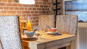 Ein Holztisch mit gewebten Stühlen, eine Orangensaftflasche, eine Schüssel mit Löffel und ein Glas Wasser.