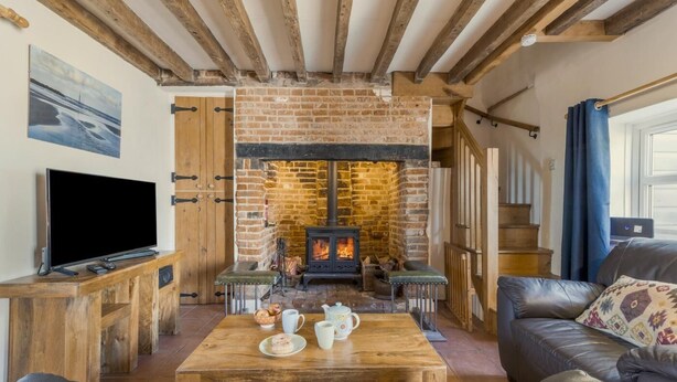 Ein gemütliches Wohnzimmer mit Kamin aus Backstein, Holzmöbeln und einem Fernseher.