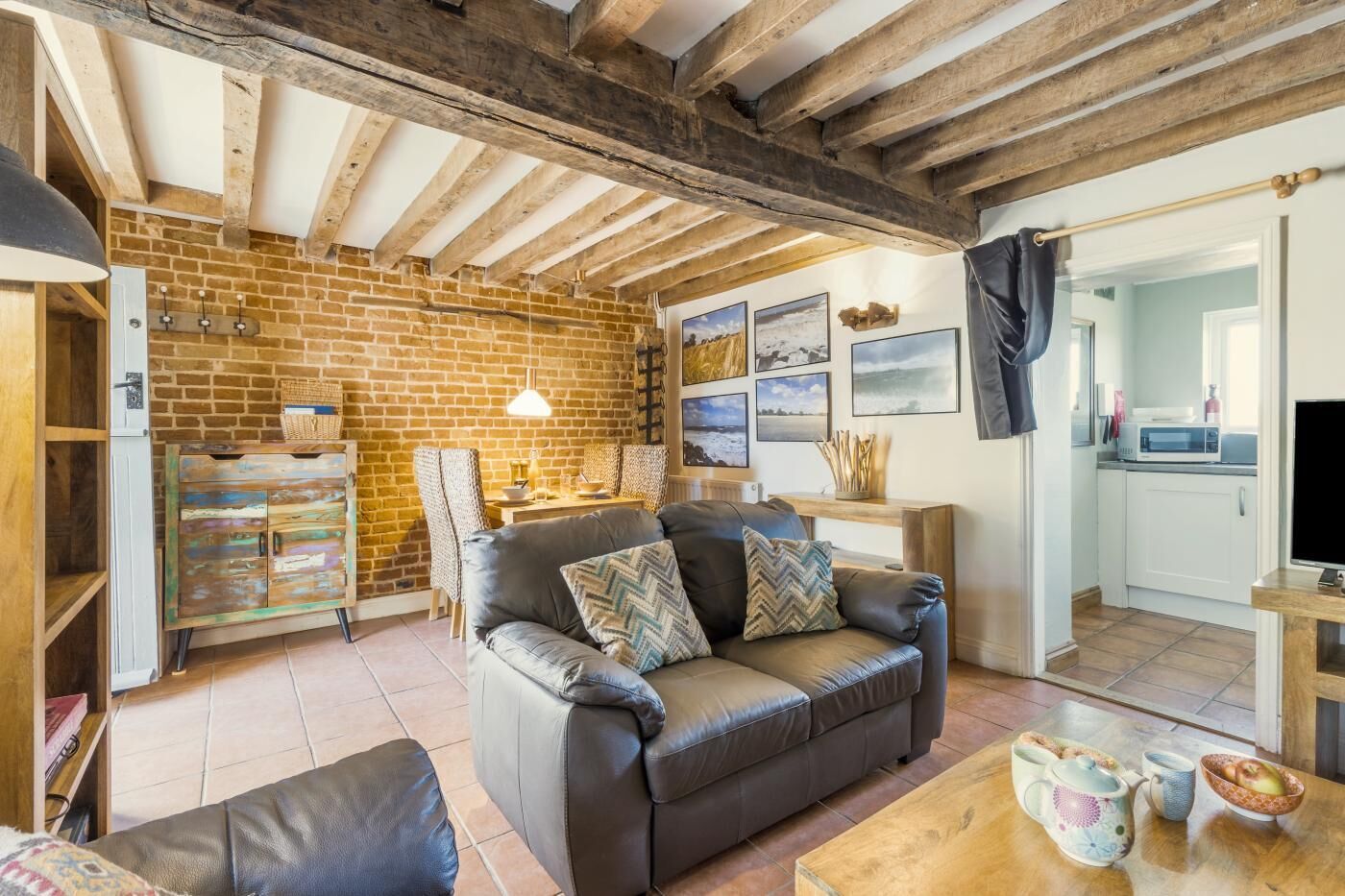 Una sala de estar acogedora con un sofá de cuero, un mueble de madera y una pared de ladrillo.