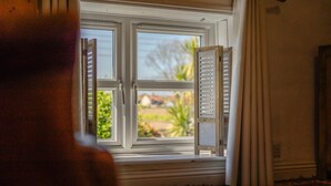 Ein Zimmer mit Fenster, Bett und Vorhang.