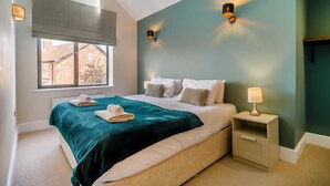 Una camera da letto con un letto, un comodino, una lampada, una finestra con persiane e vista sugli edifici esterni.