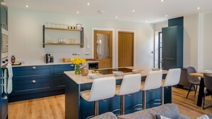 Una cucina moderna con isola centrale, sgabelli da bar e un tavolo da pranzo.