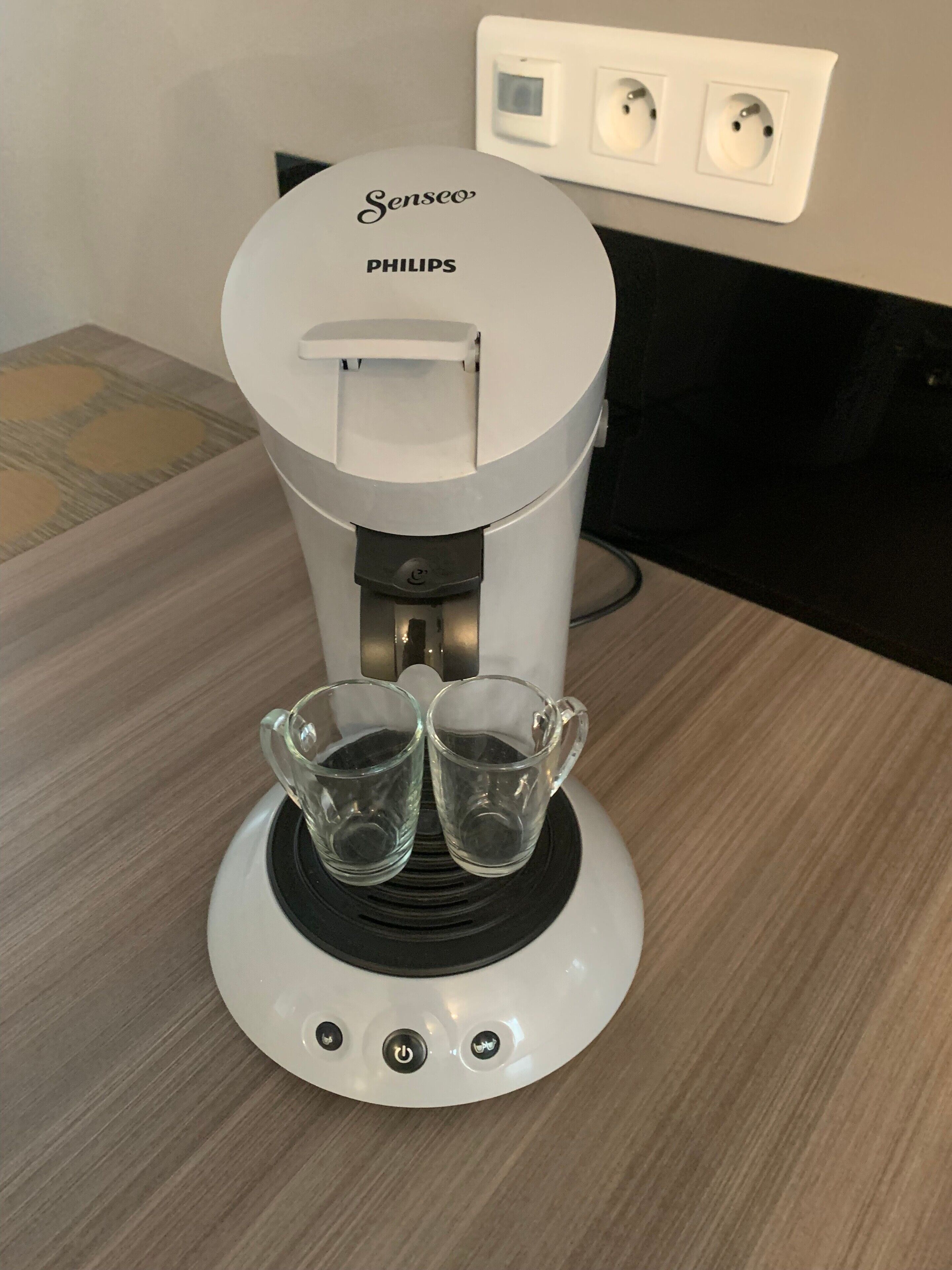 Une machine à café Senseo de Philips, avec deux verres posés sur son socle.