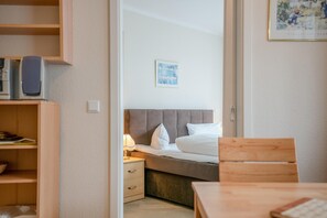 A hotel room with a bed, bedside table, lamp, and a wooden chair. - Ferienwohnung im 2.og mit Balkon in Sellin (Sellin)