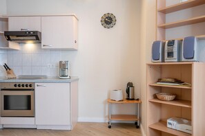A kitchen with a stove, oven, coffee maker, and a small cart with a toaster. - Ferienwohnung im 2.og mit Balkon in Sellin (Sellin)