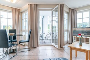 Ein modernes Zimmer mit Essbereich, Fernseher und einem Balkon mit Blick.