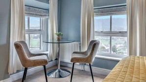 Una stanza angolare con due poltrone, un tavolino e vista panoramica da ampie finestre.