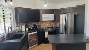 A modern kitchen with dark cabinetry, a stainless steel refrigerator, a microwave, and a sink. - Peaceful and quiet 1-bedroom condo with AC in charming Borrego Springs (Borrego Springs)