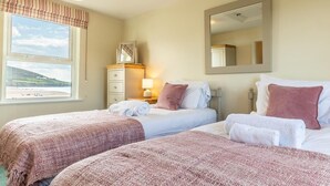 A hotel room with two beds, a window with a view of a hill, a dresser, and a mirror. - 2 Bed in Braunton (oc-87111) (Croyde)