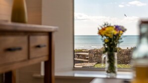Ein Zimmer mit großem Fenster, einem Holztisch und einer Vase mit Blumen.